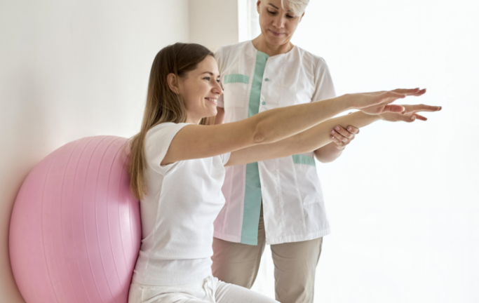 Therapist encouraging an elderly woman to perform arm stretching exercises